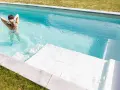 Mujer en bikini azul disfruta de una piscina cristalina, reflejo de un buen mantenimiento de piscinas.