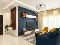 Salón moderno con pared de acento azul con relieve, combinando papel pintado y pintura. Mueble flotante con TV y decoración.