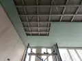 Instalación de falso techo de pladur para insonorizar habitación de ruidos de vecinos. Andamio y estructura metálica visibles.