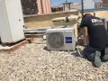 Técnico realizando mantenimiento de aire acondicionado en una azotea. Se ve una unidad Haier y otras unidades de climatización.