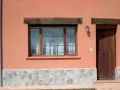 Fachada con zócalo de piedra irregular, ventana de madera y puerta rústica. Muestra distintos tipos de zócalos para paredes exteriores.