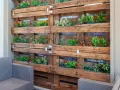 Jardineras con palets crean un jardín vertical lleno de plantas verdes y flores de colores, un oasis en el balcón.