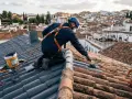 Trabajador realiza impermeabilización de tejados con pintura especial. Se ve equipo de seguridad y materiales.