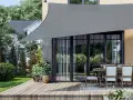 Un toldo gris protege un patio con mesa y sillas. Muestra varios tipos de toldos para exteriores, ideales para crear sombra.