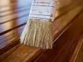 Brocha aplicando barniz a madera. Diferentes tipos de barniz para madera protegen y embellecen.