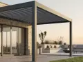 Moderna casa con terraza y **pérgola bioclimática** de lamas orientables. Sofá, tumbonas y hoguera invitan al relax.