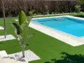 Jardín moderno con piscina y césped artificial. La colocación de césped artificial realza la belleza del espacio.