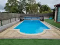 Piscina con cubierta retráctil, rodeada de césped artificial y un sistema para canalizar agua de lluvia.