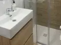 Lavabo moderno con mueble de madera y ducha acristalada. Un ejemplo de cuartos de baño modernos y funcionales.