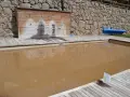 Una piscina de agua salada con un revestimiento de madera y duchas. El agua es de color marrón turbio.