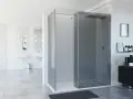 Moderno baño con mampara de ducha de esquina de cristal ahumado, lavabos dobles y accesorios elegantes.