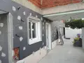 Fachada en construcción con aislamiento SATE, tuberías y ventanas.