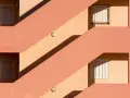 Fachada con escaleras y ventanas, sombras marcadas. Un ejemplo de cómo impermeabilizar pared exterior para protegerla.