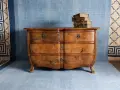Cómoda de madera antigua, lista para pintar. Unos libros apilados descansan sobre ella.