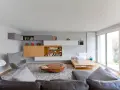 Salón moderno con estanterías empotradas y una **color crema pared**. Sofá de cuero, sillón gris y mesa de centro ovalada.