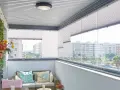 Ideas para tapar balcón: un espacio acogedor con sofá, plantas y vistas urbanas.