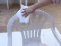 Mano limpia silla de plástico con paño, preparándola para pintura para plástico.