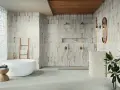 Baño moderno con bañera exenta y ducha doble. Las paredes presentan azulejos con un diseño rústico y detalles dorados, reflejando las últimas tendencias azulejos baño.