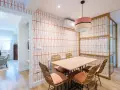 Comedor con pared empapelada con un diseño geométrico en naranja. Mesa de madera con sillas de ratán y cojines terracota.