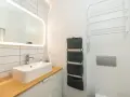 Moderno baño pequeño con lavabo sobre encimera de madera, espejo iluminado y organizadores de pared. ¡Una reforma de baño pequeño funcional y estilosa!