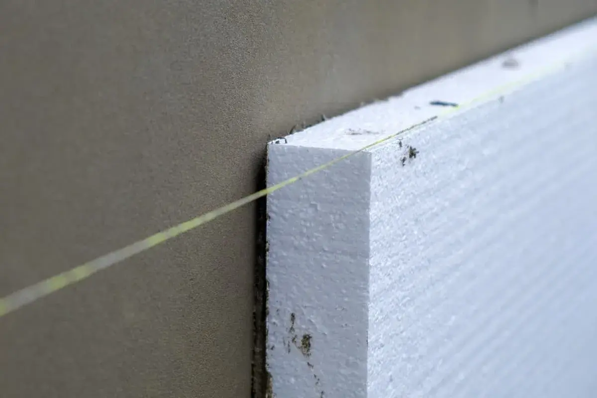 Instalación de materiales aislantes de poliestireno expandido en una pared, guiada por un hilo.