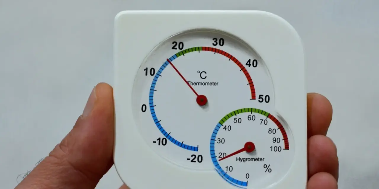 Termómetro y higrómetro en mano, mostrando cómo medir la humedad en casa.