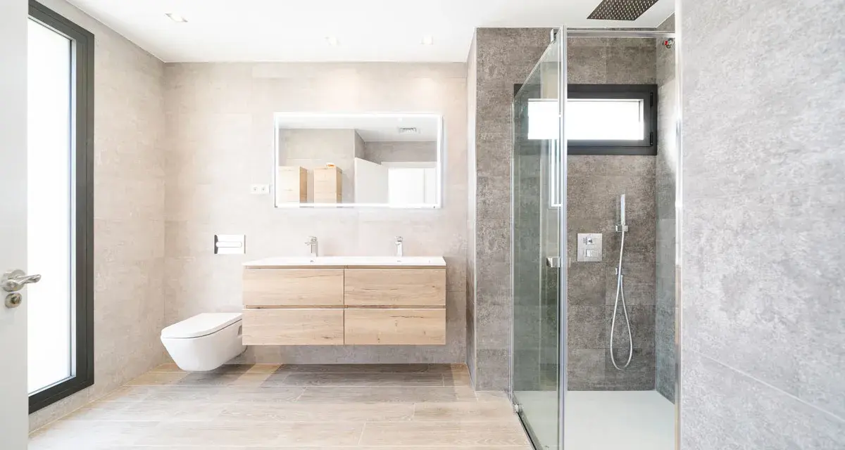 Baño moderno con ducha de cristal, lavabo flotante y WC suspendido. La fontanería se integra con estilo, cuidando cada altura y medida.