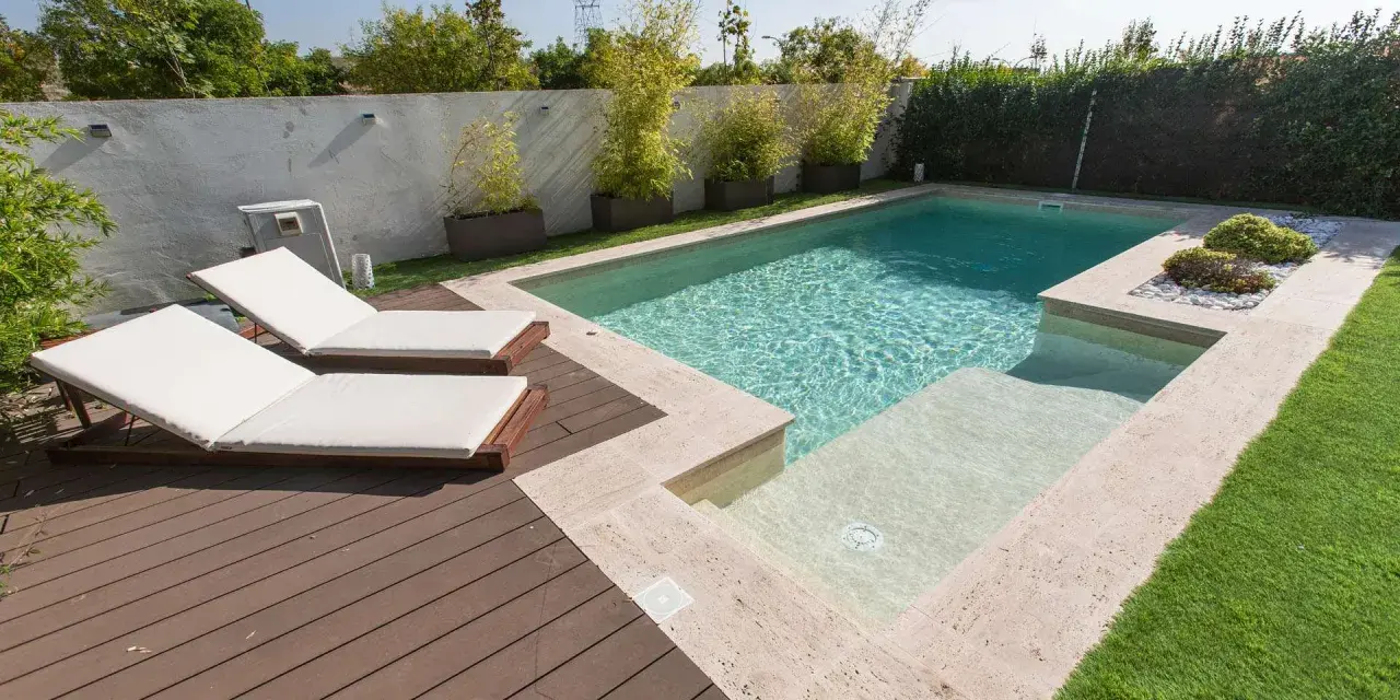 Modern pool with deck, lounge chairs, and bamboo plants. Great ideas para decorar alrededor de la piscina para un oasis de verano.