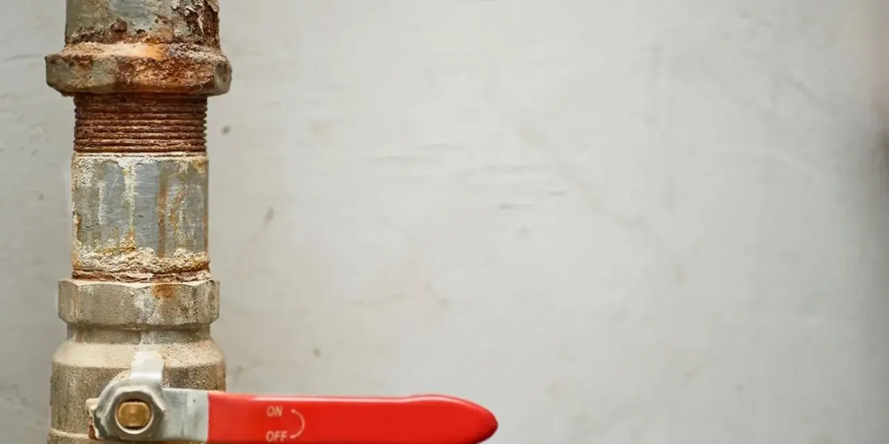 Tubería oxidada con llave de paso roja, lista para cambiar llaves de paso antiguas.