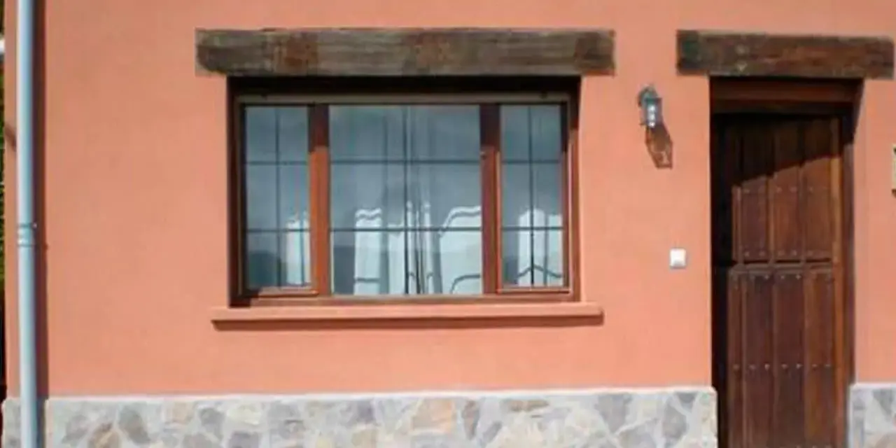 Fachada con zócalo de piedra irregular, ventana de madera y puerta rústica. Muestra distintos tipos de zócalos para paredes exteriores.