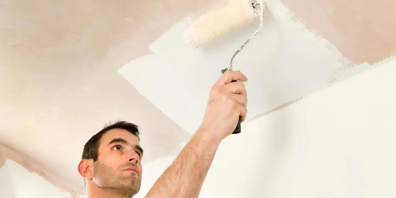 Hombre pintando el techo con rodillo. La pregunta de si que se pinta primero el techo o las paredes es clave para un buen acabado.