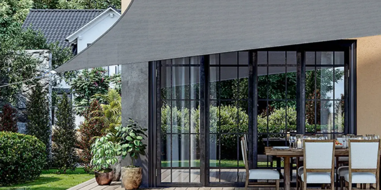 Un toldo gris protege un patio con mesa y sillas. Muestra varios tipos de toldos para exteriores, ideales para crear sombra.