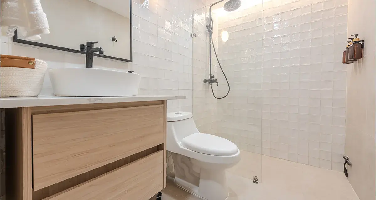 Baño moderno con lavabo sobre mueble de madera, inodoro y ducha con azulejos blancos. ¡Un proyecto de pintar azulejos baño que inspira!