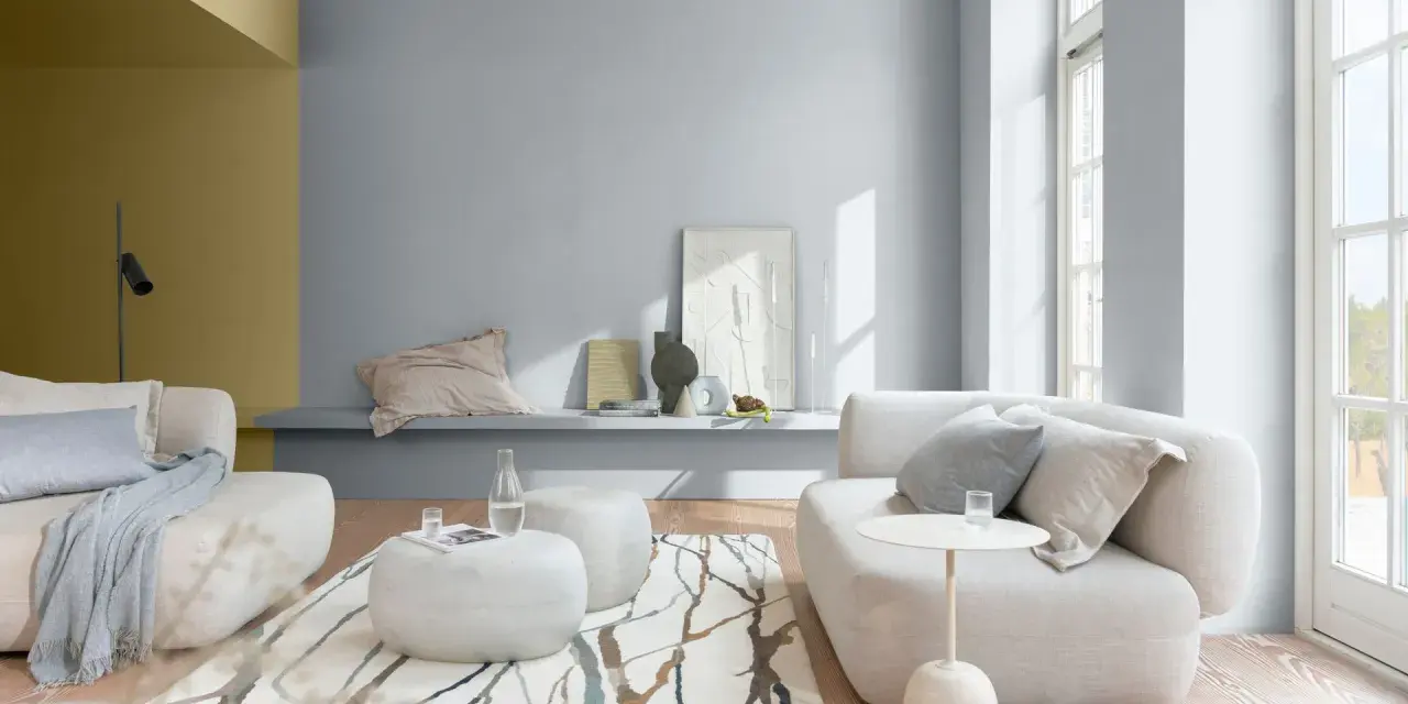 Salón moderno con sofás blancos, alfombra de ramas y paredes en pintura al agua gris y ocre.