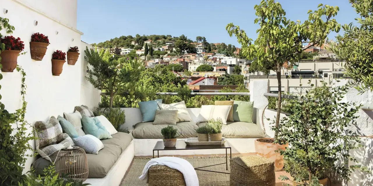 Un espacio perfecto para **chill out** en la **terraza**, con cómodos cojines, plantas y vistas a la ciudad.