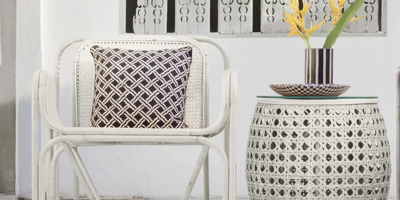 Sillón y mesa auxiliar de mimbre blanco, con cojín estampado y flores amarillas. Ideas de colores para pintar mimbre.