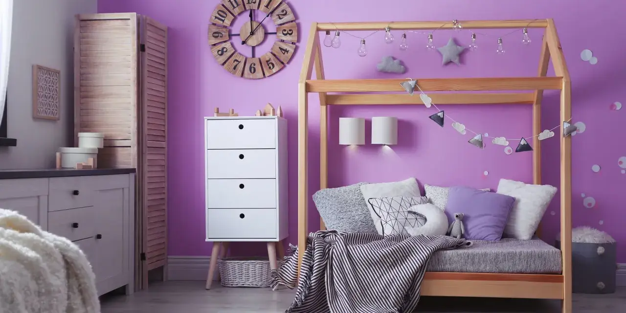 Adolescentes pintan habitación juvenil. Un espacio lleno de color lila, con cama de madera, cómoda blanca y decoración infantil.