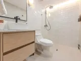 Baño moderno con lavabo sobre mueble de madera, inodoro y ducha con azulejos blancos. ¡Un proyecto de pintar azulejos baño que inspira!