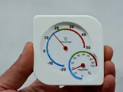 Termómetro y higrómetro en mano, mostrando cómo medir la humedad en casa.