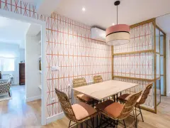 Comedor con pared empapelada con un diseño geométrico en naranja. Mesa de madera con sillas de ratán y cojines terracota.