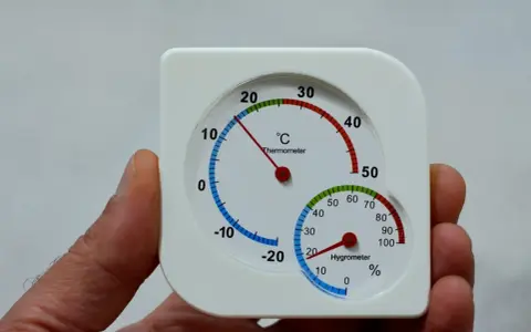 Termómetro y higrómetro en mano, mostrando cómo medir la humedad en casa.