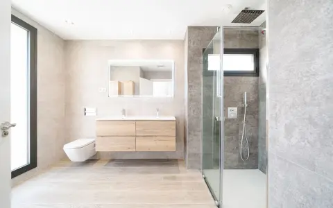 Baño moderno con ducha de cristal, lavabo flotante y WC suspendido. La fontanería se integra con estilo, cuidando cada altura y medida.