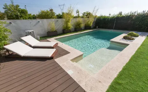 Modern pool with deck, lounge chairs, and bamboo plants. Great ideas para decorar alrededor de la piscina para un oasis de verano.