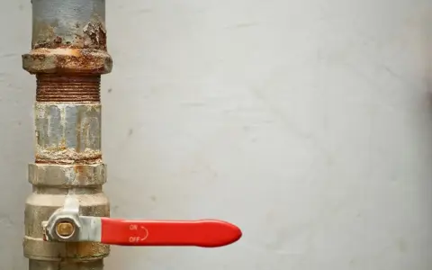 Tubería oxidada con llave de paso roja, lista para cambiar llaves de paso antiguas.