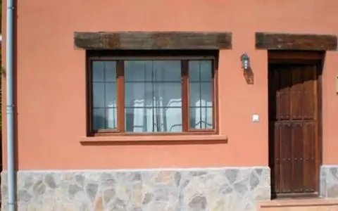 Fachada con zócalo de piedra irregular, ventana de madera y puerta rústica. Muestra distintos tipos de zócalos para paredes exteriores.