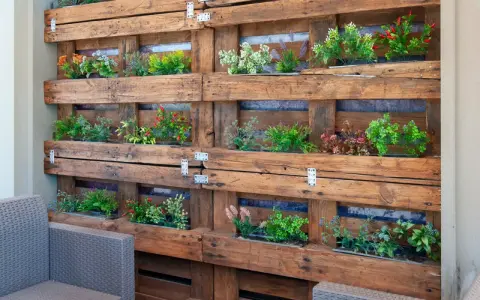 Jardineras con palets crean un jardín vertical lleno de plantas verdes y flores de colores, un oasis en el balcón.