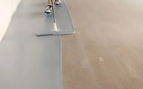 Aplicando pintura epoxi gris sobre un suelo de hormigón. El proceso de aplicación de la pintura epoxi transforma el espacio.
