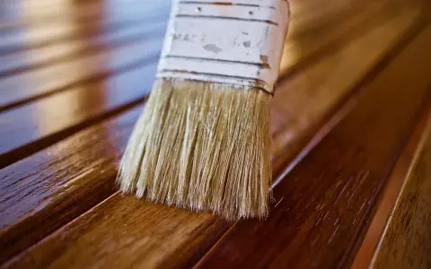 Brocha aplicando barniz a madera. Diferentes tipos de barniz para madera protegen y embellecen.