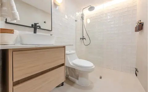 Baño moderno con lavabo sobre mueble de madera, inodoro y ducha con azulejos blancos. ¡Un proyecto de pintar azulejos baño que inspira!