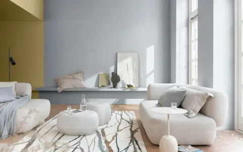 Salón moderno con sofás blancos, alfombra de ramas y paredes en pintura al agua gris y ocre.